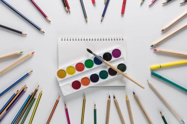 Üstten görünüm üzerinde bir okul tablo kalemleri ile boya ve fırça ortasında beyaz bir arka plan üzerinde bir daire yerleştirilir. Geri okul kavramı. Ofis malzemeleri düz yatıyordu.