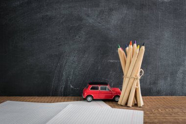 Bir grup küçük kırmızı araba oyuncak yakınındaki bir iple bağlı kalemler üzerinden yan görünüm. Geri okul kavramı