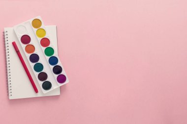 Üstten görünüm üzerinde bir okul malzemeleri dizüstü bilgisayarlar, kalem ve pembe bir arka plan sol tarafındaki boyalar. Geri okul kavramı. Ofis malzemeleri düz yatıyordu.