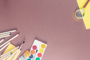 Okul ile kahverengi bir arka plan üzerinde üstten görünüm üzerinde sağlar. Boyalar, fırçalar, dizüstü bilgisayarlar, iki taraftan da muhteşem cam. Geri okul ve eğitim kavramı