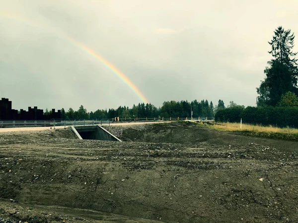 Drizzle on the windshield while driving in rain. Wet road and rainbow in the sky