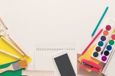 En iyi görünümü üzerinde bir dizüstü bilgisayarlar, boyalar, kalemler, cetveller, ataç, iğne, hesap makinesi, tutkal, kalemtıraş, kalem, kağıt üzerinde beyaz bir arka plan. Geri okul kavramı. Ofis malzemeleri düz yatıyordu