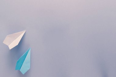 Mavi arka plan üzerinde iki uçan kağıt uçak. Geri okul ve eğitim kavramı. Seyahat ve Turizm sembolü olarak uçak.