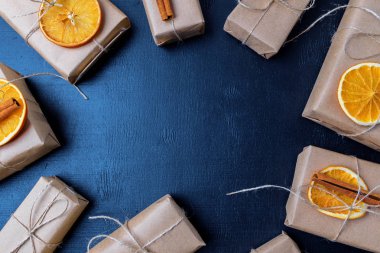 Kraft kağıt, dryed portakal ve tarçın çemberde yer Noel hediye kutuları ile bir tahta arka plan üzerinde üstten görünüm Paketli. Yat, uzay, tatil afiş Kopyala.