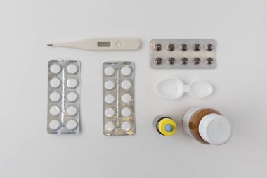 Üstten görünüm hapları, termometre, syrips ve damla, kaşık tıbbi sıvılar için ölçme ile farklı şişe ile bir model üzerinde. Grip ve mevsimsel hastalıklar kavramı