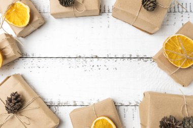 Noel hediye kutuları ile beyaz ahşap zemin üzerinde üstten görünüm Kraft kağıt dryed portakal ve çam üstüne ile paketlenmiş. Yat, uzay, tatil afiş Kopyala.