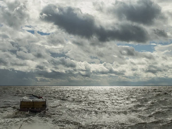 tekne güneşli bir Ağustos rüzgarlı günde Vozhe Gölü dalgaları için orta güçlü bir yük ile küçük bir mavna çeker