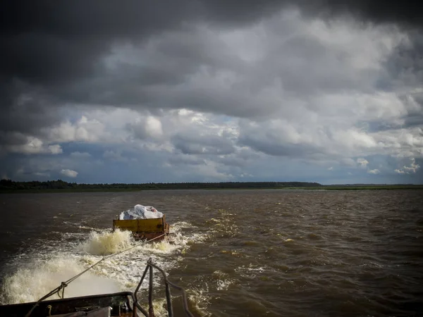 tekne güneşli bir Ağustos rüzgarlı günde Vozhe Gölü dalgaları için orta güçlü bir yük ile küçük bir mavna çeker