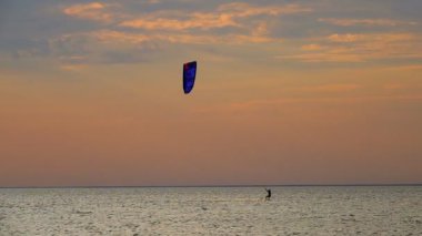 ağır çekim Genç adam Kitesurfing dalgalar halinde batan güneşin üzerinde pratik