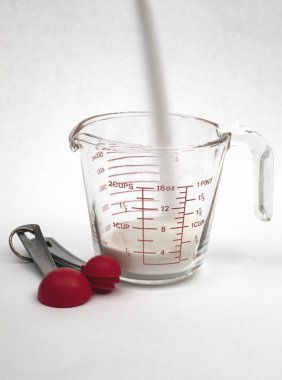 Beyaz şeker kamışı bir ölçme fincan dökme ile ölçme kaşık görünümünde, saat pozlama.