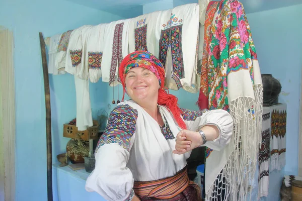 The photo was taken in one of the villages of Transcarpathia in Ukraine. The picture shows a young woman in national dress. The interior of the national village house is visible in the background.