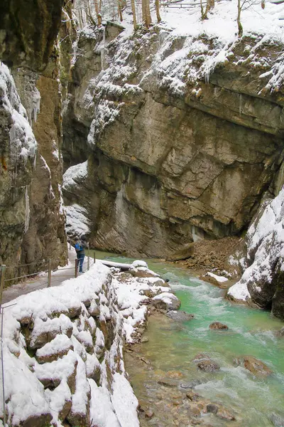 The photo was taken in Germany, in the mountains near the town of Garmisch-Partenkirchen. The picture shows the trail along the bottom of the gorge along the mountain river. On the trail you can see a young man traveling in the mountains.