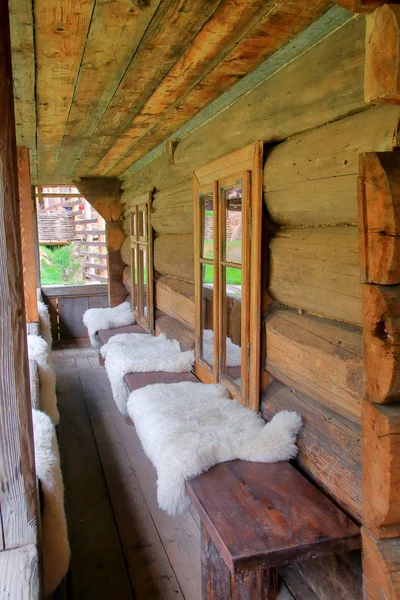 Banc avec des peaux drapées de moutons devant l'entrée de la — Photo