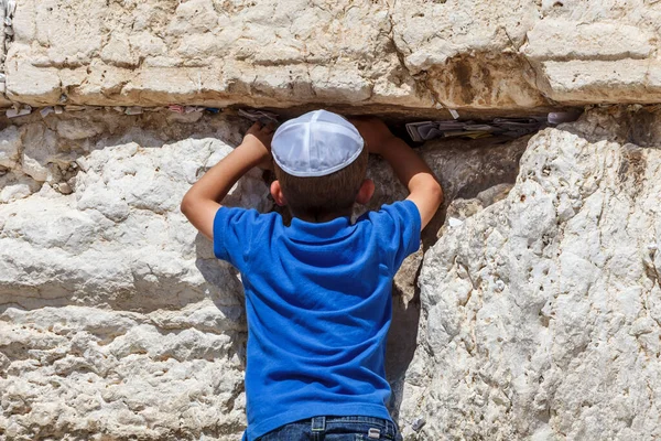 一个犹太小男孩在耶路撒冷的西墙前祈祷 在石头缝隙中带着祈祷和祝福的音符 — 图库照片
