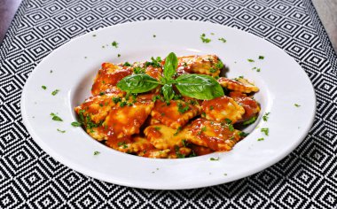 Taze Mantı makarna maydanoz ve fesleğen yaprağı, İtalyan mutfağı ile. Beyaz plaka ve ahşap masa, makarna yemek.