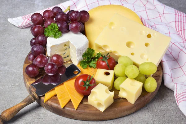 Lezzetli peynir tabağı ile çeşitli tür-in beğenmek Emmentaler, gouda ve brie peyniri. Gurme peynir beyaz beton arka plan ve Mutfak havlu ile ahşap kesme tahtası.