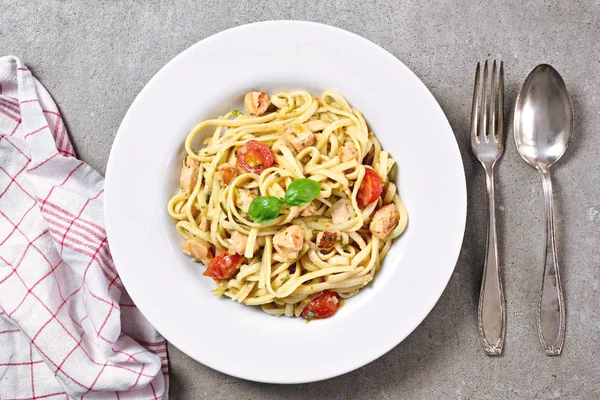 Delicious salmon pasta dish, tagliatelle or linguine noodles. High angle view of fresh spaghetti pasta with herbs and cherry tomatoes.