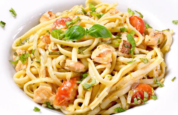 Delicious salmon pasta dish, tagliatelle or linguine noodles. High angle view of fresh spaghetti pasta with herbs and cherry tomatoes.