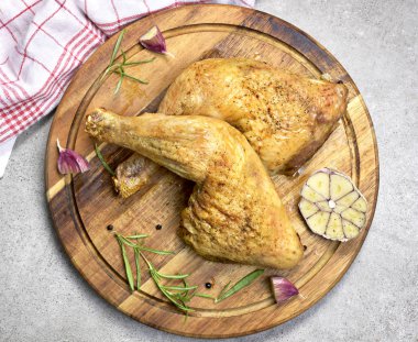 Lezzetli kızarmış tavuk but ya da tavuk drumsticks ahşap kesme tahtası üzerinde. Yüksek açılı görünüş ve taze biberiye ve sarımsak. Atış, Closeup üstten görünüm.