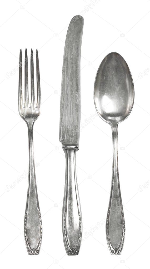 Vintage cutlery, silverware. Old silver cutlery, isolated on white background. Top view of table knife, fork and spoon with ornament details.