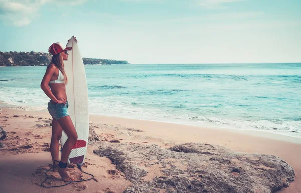 夏休みとウォーター スポーツを楽しむサーフボード 完璧なボディと魅力的な陽気な女性が付いている浜に立って美しいサーファーの女の子 — ストック写真