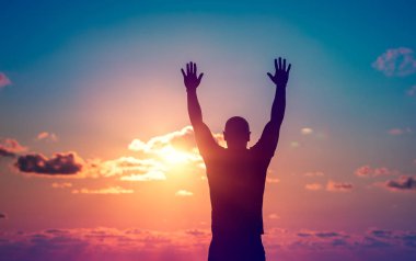 Bir adamla silüeti açık havada akşam ayakta eller yukarı kaldırdı, inanılmaz yaşam ve Özgürlük kavramı keyfi güzel günbatımı gökyüzü görünümünü contemplates