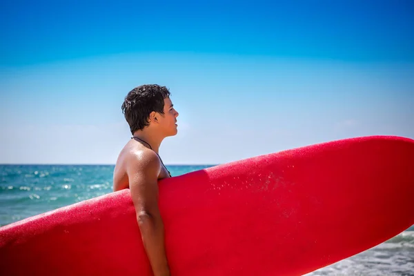 Guapo Adolescente Pie Playa Con Una Tabla Surf Roja Feliz —  Fotos de Stock