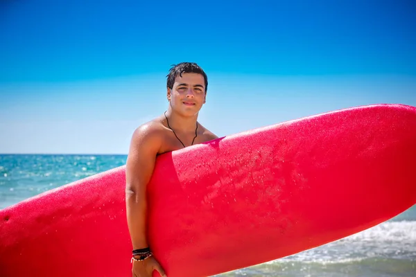 ウォーター スポーツは 幸せな Seashor の陽気な夏の休日を楽しんでビーチで赤のサーフボードと十代の少年 — ストック写真