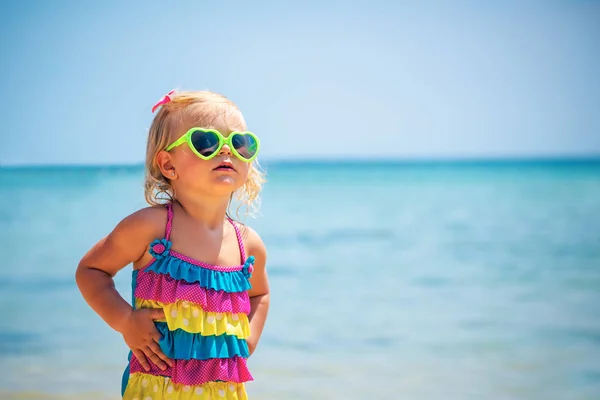 可爱的小金发女孩在海滩上戴着墨镜和时髦的彩色泳装 孩子的时尚 暑假附近的海边 — 图库照片