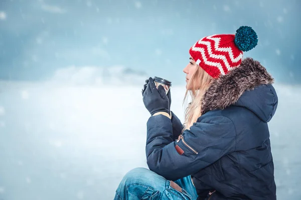 雪の冬の日に外に座ってコーヒーを飲みながら 穏やかな冬の休暇を楽しんでいる素敵な女の子 — ストック写真