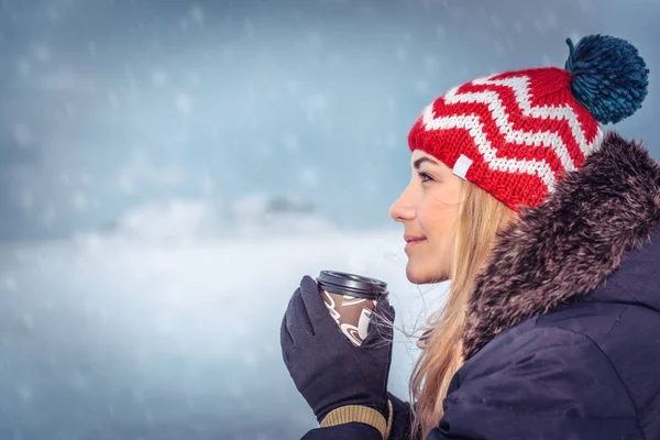 寒い冬の時期の で屋外楽しんで雪の日を楽しむ手のホット コーヒーのマグカップをスタイリッシュな暖かい帽子身に着けている美しい女性の肖像画 — ストック写真