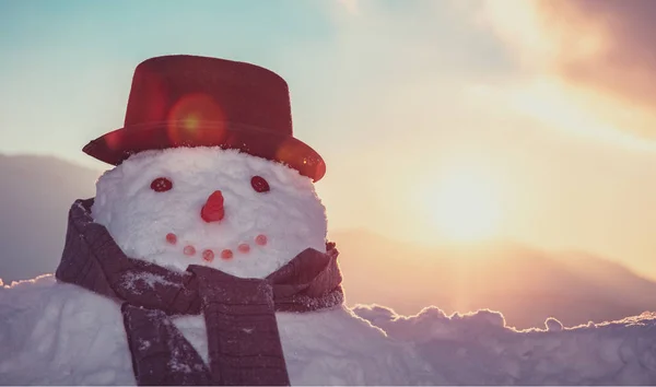 穿着帽子和围巾的雪人在日落背景下的画像 有趣的冬季传统 快乐的寒假 — 图库照片