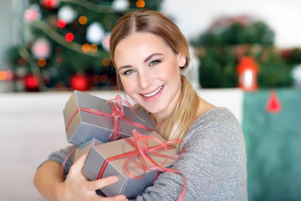 一个漂亮的快乐女人的画像 手里拿着礼品盒坐在一个漂亮的装饰房间里 度过了一个快乐的圣诞假期 — 图库照片