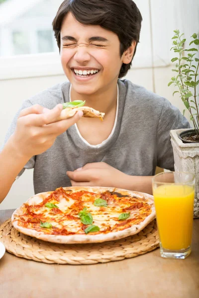 幸せな10代の男の子の肖像画喜びはピザを食べ 笑って 陽気な10代の若者はおいしい食べ物を楽しんで 家で素晴らしい週末を過ごす — ストック写真