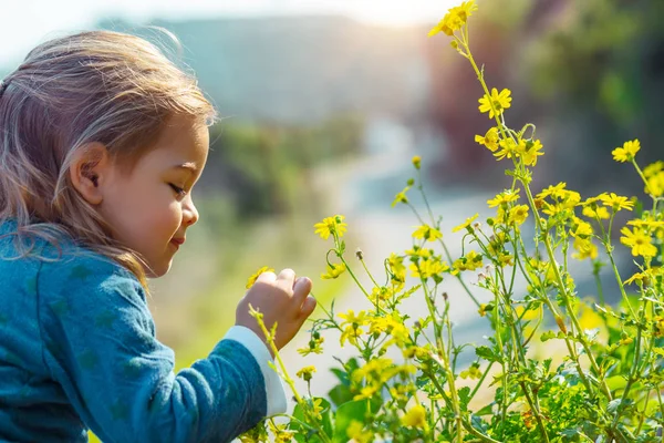 Дитина насолоджується ароматом квітів — стокове фото