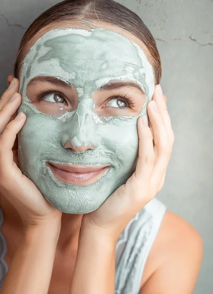 Happy woman doing mask of a clay — Stock Photo, Image