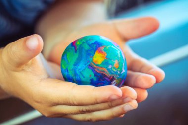 Conceptual Photo of a Saving the Planet, Babie's Hands Holding Little Earth, Made of Plasticine, Future of the Planet, Pollution Free. clipart