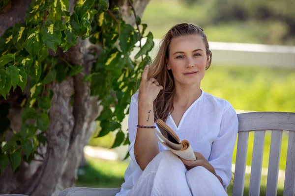 Yaz parkında, bankta oturan ve zevkle kitap okuyan hoş bir kadının portresi. İlginç Hikaye 'nin tadını çıkar. Eğitim açık havada. - Boş zaman. Huzurlu Yaz Tatiliniz Kutlu Olsun