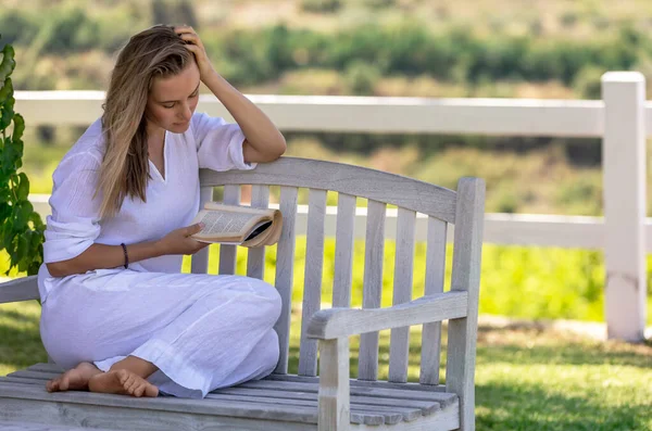 美しい若い女性が公園のベンチに座って本を読んでいます 良い話で素敵な夏の日を過ごす 平和とリラクゼーションの概念 — ストック写真