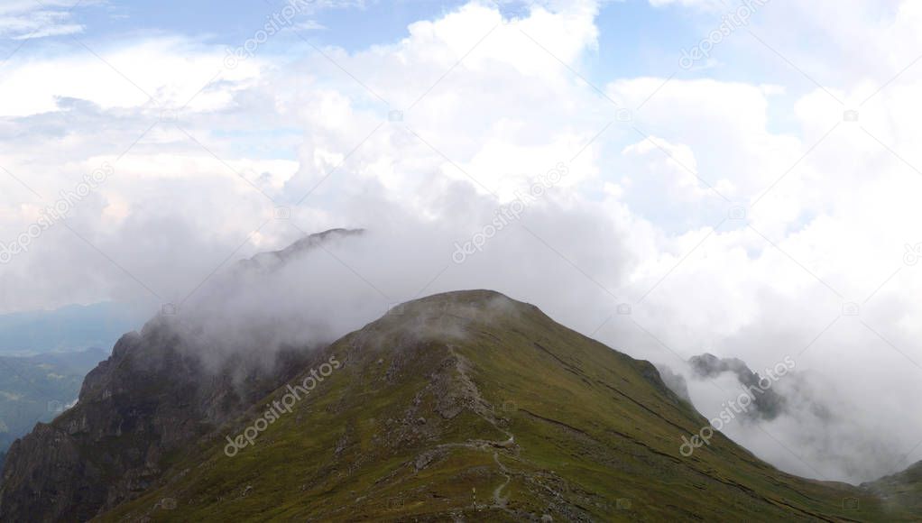 Panorama with mountain ridges and white clouds climbing from the valley - Romania, Bucegi