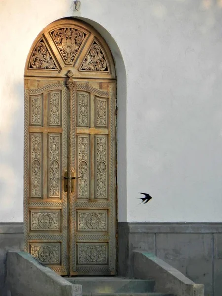 The sculpted door of a church and a row in flight — Stock Photo, Image