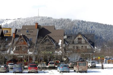 Zakopane, Polonya - 21 Mart 2018: bir kaç konut ev Gubalowka olarak adlandırılan bir tepenin arka planı görülebilir. Birkaç araba yerel otoparkında park yerleri park