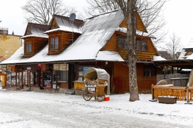 Zakopane, Polonya - 19 Mart 2018: Geleneksel tasarım ile ahşap bir bina karla kaplı Krupowki Caddesi üzerinde yer alır. Ayrıca bölgesel gıda ürünleri ile küçük bir stand olduğunu.