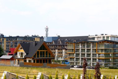 Zakopane, Polonya - 17 Ağustos 2017: modern otel binası çok sayıda Konuklar için tasarlanmış. Otelin önünde geleneksel mimari özellikleri ile modern bir yerleşim ev yoktur.