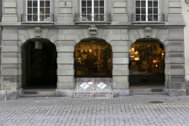 Bern, Switzerland - February 21, 2018: There are many shops along the arcades and a slightly inclined cellar entrance door is visible on the outside. This is a famous detail of this part of the city