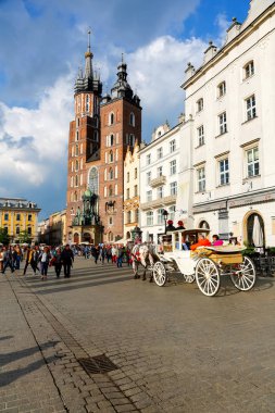 Krakow, Polonya - 25 Mayıs 2017: Old Town ana pazar meydanında bulunan St. Mary's kilise yönünde beyaz arabayı şehir hayran turist ile gider. 