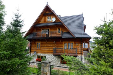 Zakopane, Poland - August 17, 2017: Traditional residential house built of wooden logs. The outer walls of its ground floor are made of large stones.