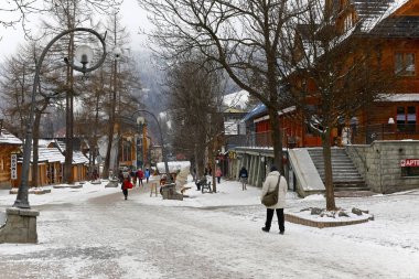 Zakopane, Polonya - 19 Mart 2018: Sadece birkaç yayalar ünlü promenade yürümek. Krupowki Street orada her iki tarafta binaların çoğu ve kaldırım yüzeye kar yatıyor