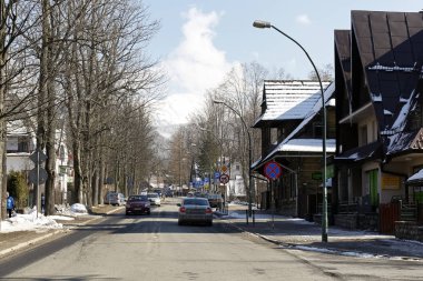 Zakopane, Polonya - 22 Mart 2018: Trafik şehrin caddeleri üzerinde. Cadde boyunca pek çok ağaç ve uzaktan onlara kar ile Dağları vardır.