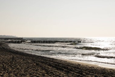 Güneş yavaş yavaş plaj üzerinde ayarlamak başlar. Eski ahşap groyne sahile Kolobrzeg, Polonya dalgalar deniz uğursuz etkilerine karşı korur